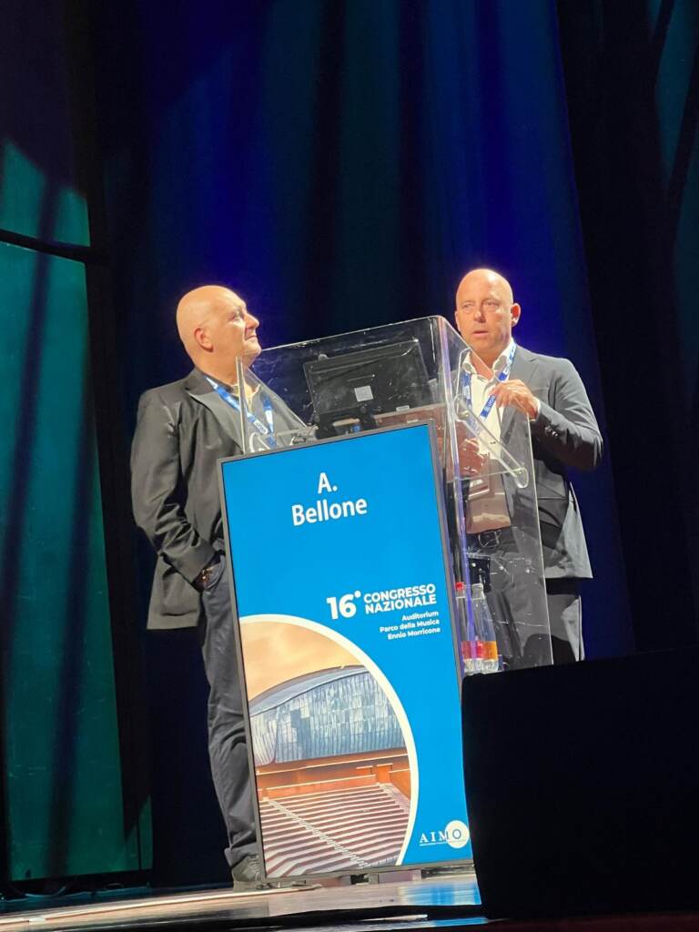 Il Dott. Alberto Bellone e il Dott. Galli sul palco del Congresso AIMO 2026 durante la presentazione del caso